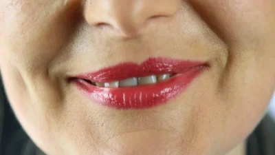 Close-up of a bright red lipstick stain on white fabric, showing how the pigment spreads into the fibers.