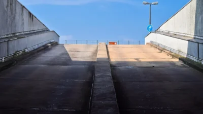 Close-up of dark oil stains on a gray concrete driveway with cleaning supplies nearby.
