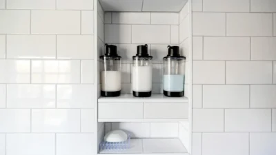 Close-up of soap scum buildup on white bathroom tile and chrome shower fixture