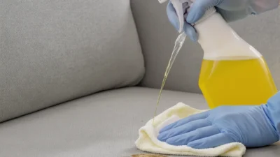 Close-up of a person performing a spot test on a fabric sofa cushion before stain removal.